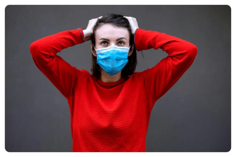 Madre con mascarilla llevándose las manos a la cabeza, preocupada